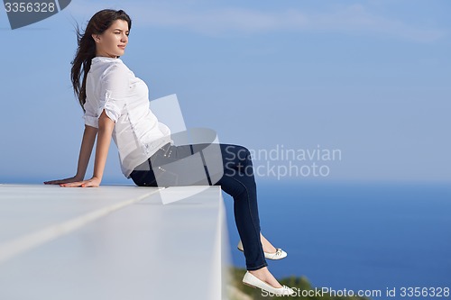 Image of relaxed woman in front of luxury modern home