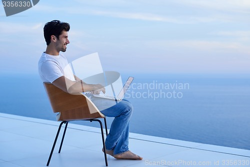 Image of relaxed young man at home on balcony