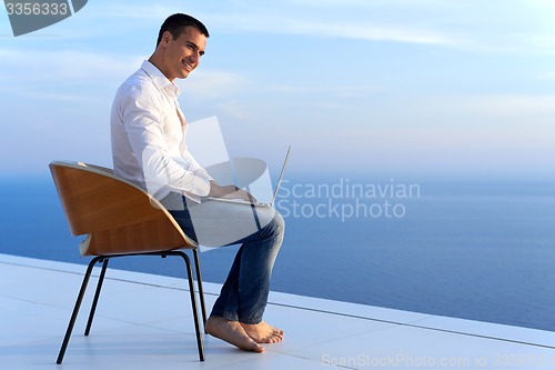 Image of relaxed young man at home on balcony