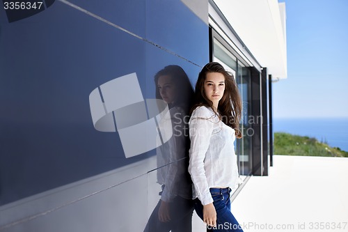 Image of relaxed woman in front of luxury modern home