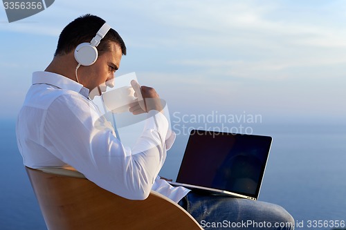 Image of relaxed young man at home on balcony