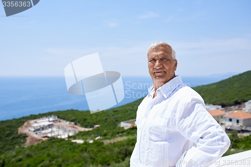 Image of senior man in front of modern home