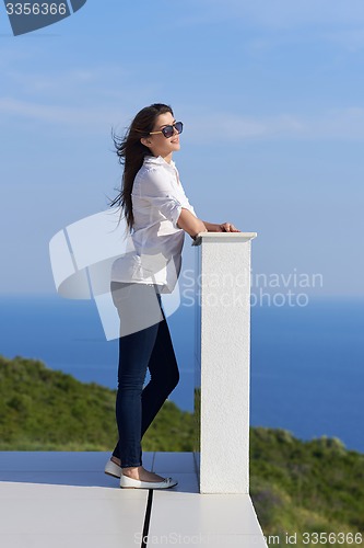 Image of relaxed woman in front of luxury modern home