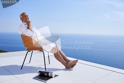 Image of senior man in front of modern home