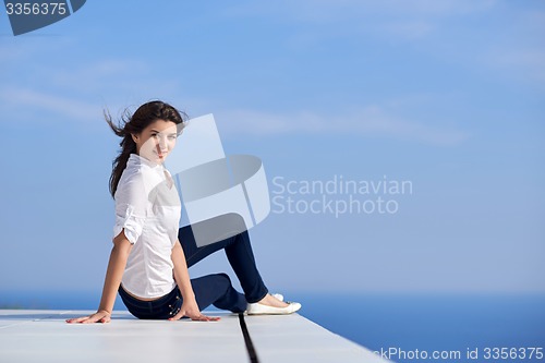 Image of relaxed woman in front of luxury modern home