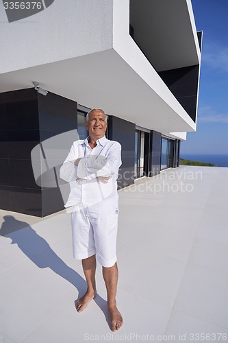 Image of senior man in front of modern home