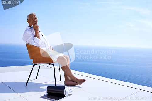 Image of senior man in front of modern home