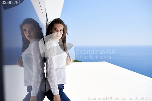 Image of relaxed woman in front of luxury modern home