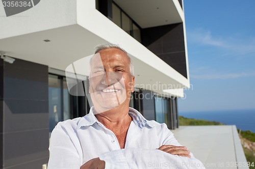 Image of senior man in front of modern home