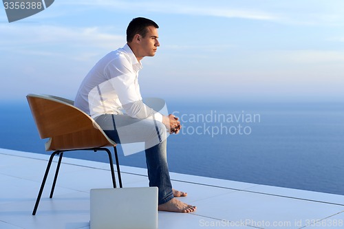 Image of relaxed young man at home on balcony