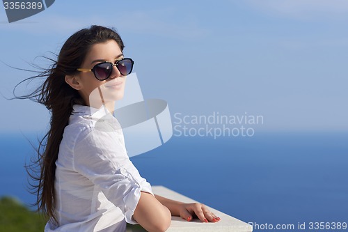 Image of relaxed woman in front of luxury modern home