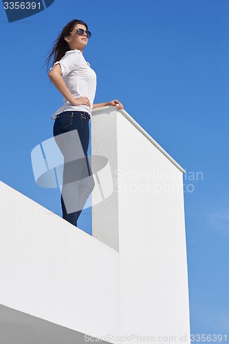 Image of relaxed woman in front of luxury modern home