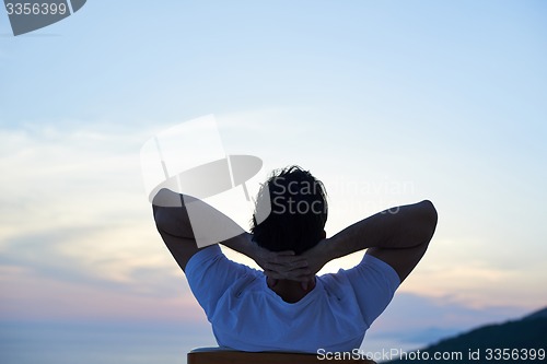 Image of relaxed young man at home on balcony