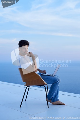 Image of relaxed young man at home on balcony