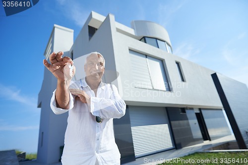 Image of senior man in front of modern home