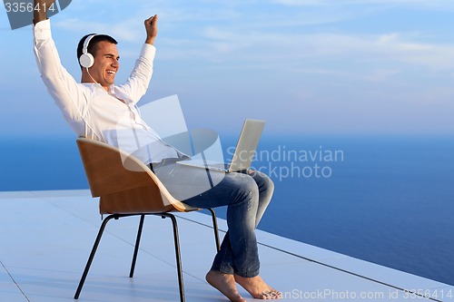 Image of relaxed young man at home on balcony