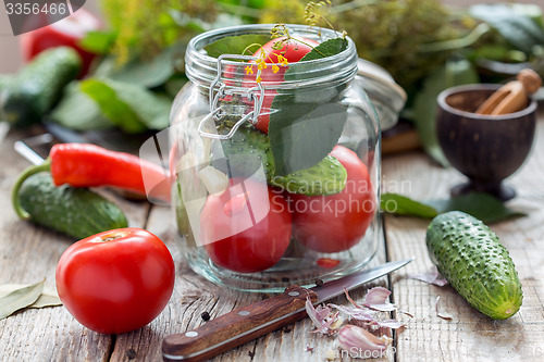Image of Vegetables and herbs in the glass jar on a wooden table.