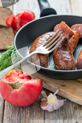 Image of Fork and fried sausage in a skillet.