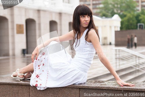 Image of Attractive sad girl sits near city theater