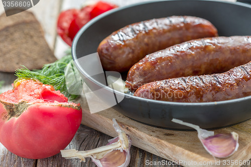 Image of Fried sausage, tomato and garlic closeup.