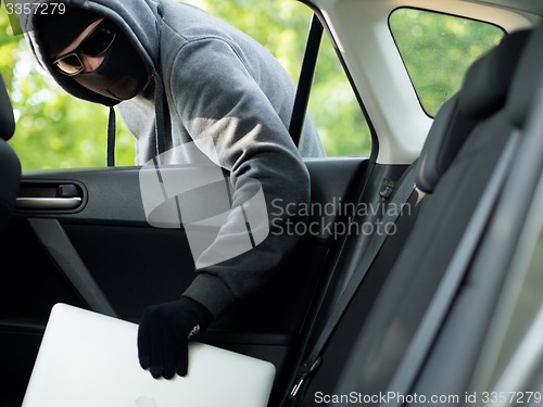 Image of Car theft - a laptop being stolen through the window of an unoccupied car.