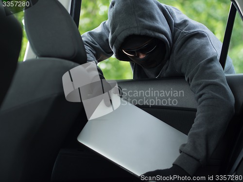 Image of Car theft - a laptop being stolen through the window of an unoccupied car.