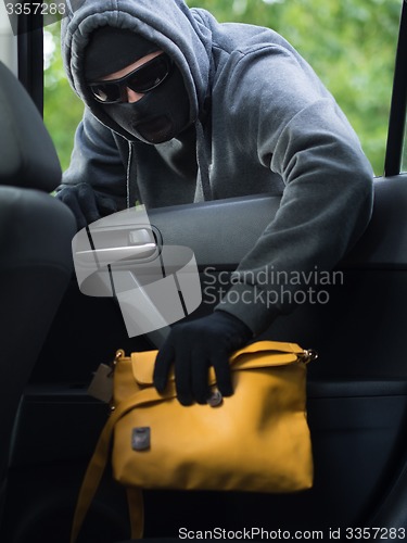 Image of Transportation crime concept .Thief stealing bag from the car