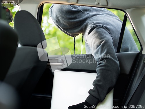 Image of Car theft - a laptop being stolen through the window of an unoccupied car.