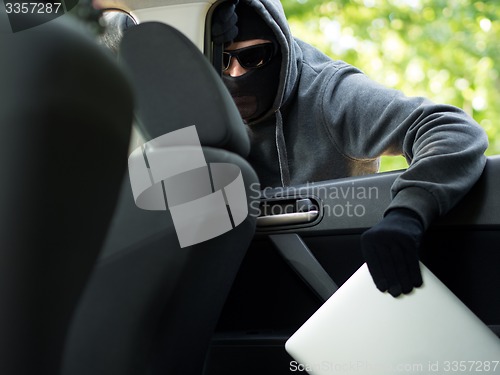 Image of Car theft - a laptop being stolen through the window of an unoccupied car.