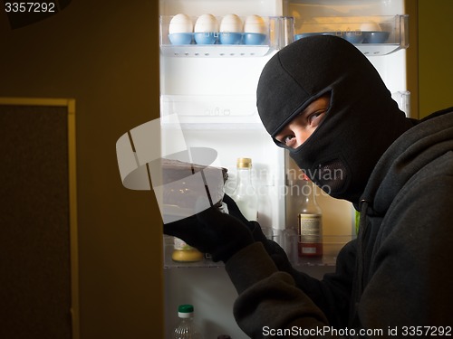 Image of Thief. Man in black mask with a cake.