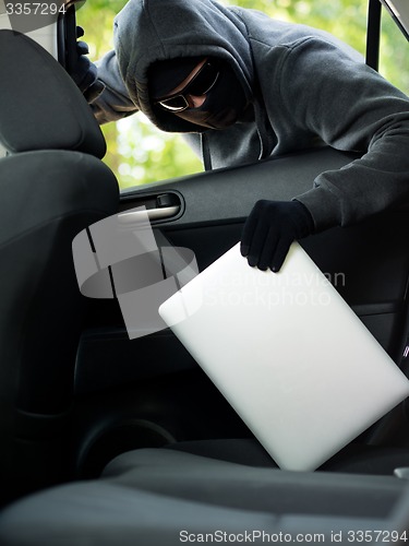 Image of Car theft - a laptop being stolen through the window of an unoccupied car.