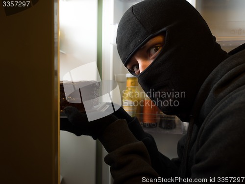 Image of Thief. Man in black mask with a cake.