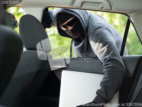 Image of Car theft - a laptop being stolen through the window of an unoccupied car.