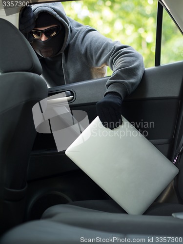 Image of Car theft - a laptop being stolen through the window of an unoccupied car.