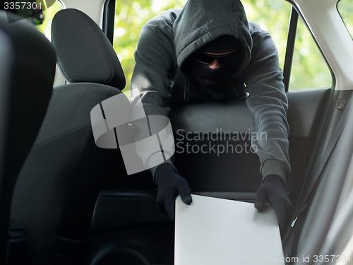 Image of Car theft - a laptop being stolen through the window of an unoccupied car.