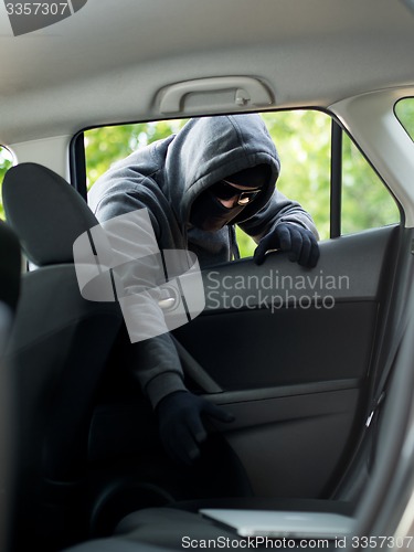 Image of Car theft - a laptop being stolen through the window of an unoccupied car.