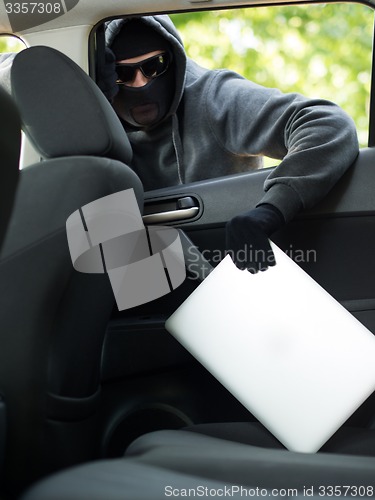 Image of Car theft - a laptop being stolen through the window of an unoccupied car.