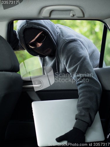 Image of Car theft - a laptop being stolen through the window of an unoccupied car.