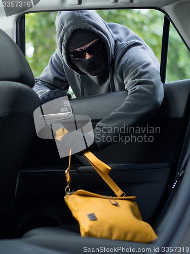Image of Transportation crime concept .Thief stealing bag from the car