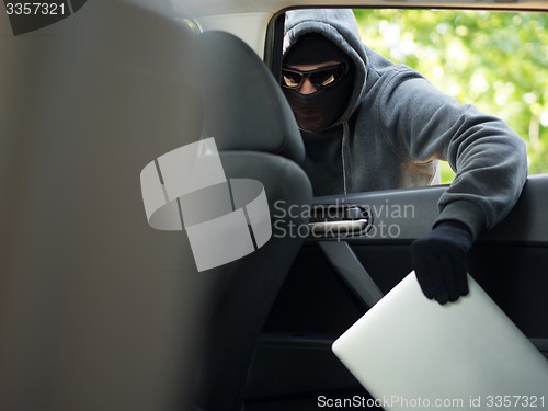 Image of Car theft - a laptop being stolen through the window of an unoccupied car.