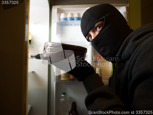 Image of Thief. Man in black mask with a cake.