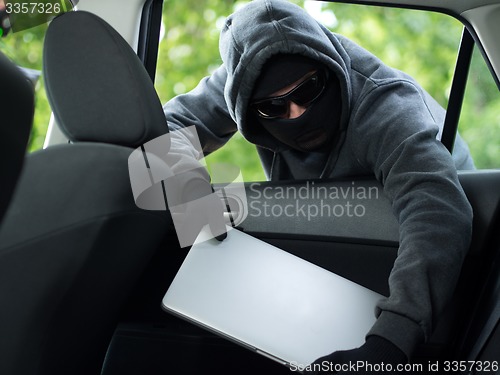 Image of Car theft - a laptop being stolen through the window of an unoccupied car.