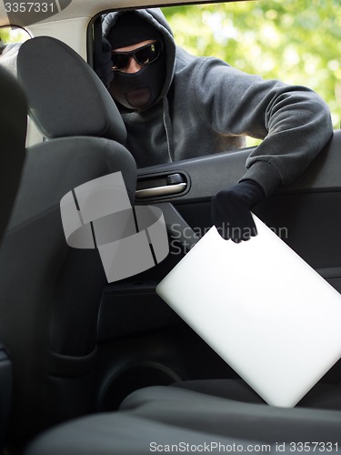 Image of Car theft - a laptop being stolen through the window of an unoccupied car.