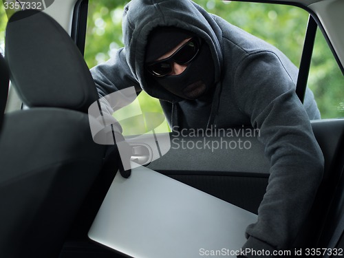 Image of Car theft - a laptop being stolen through the window of an unoccupied car.