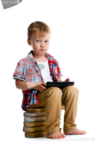 Image of Little boy with a tablet computer sitting on the books