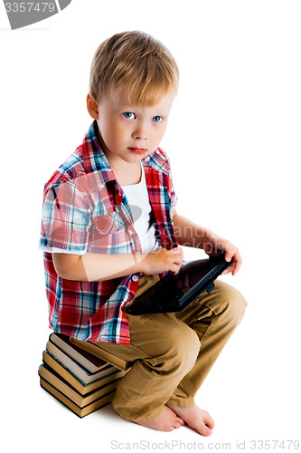 Image of Little boy with a tablet computer sitting on the books