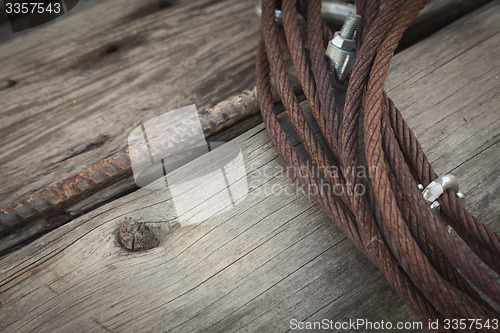 Image of Abstract Rusty Iron Cable Laying on Old Wood Planks