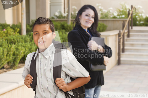 Image of Hispanic Boy with Backpack on School Campus and Teacher Behind