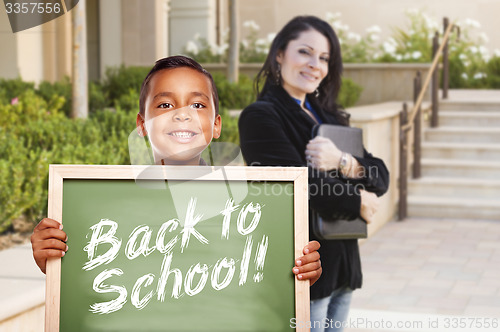 Image of Boy Holding Back To School Chalk Board with Teacher Behind