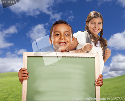 Image of Hispanic Boy and Girl In Field Holding Blank Chalk Board